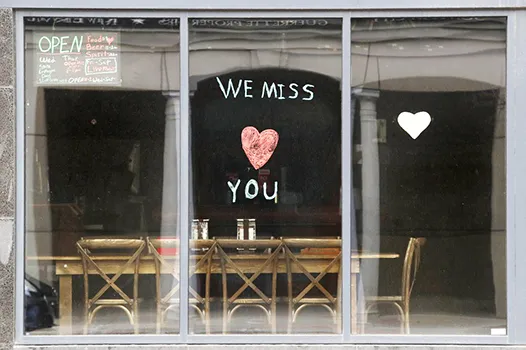 Sign in the window of empty cafe saying, "We miss you"