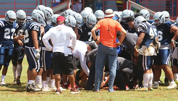 Samoana Sharks varsity squad huddling around one of their injured players