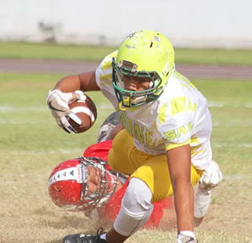 A Leone Lions running back is dragged down in the backfield by a Viking defender