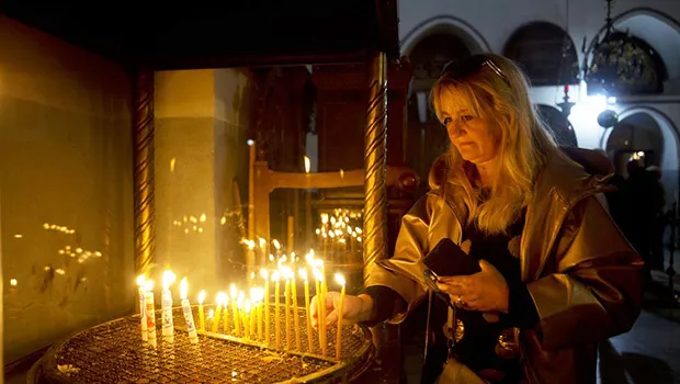 A visitor lights a candle at the Church of the Nativity built