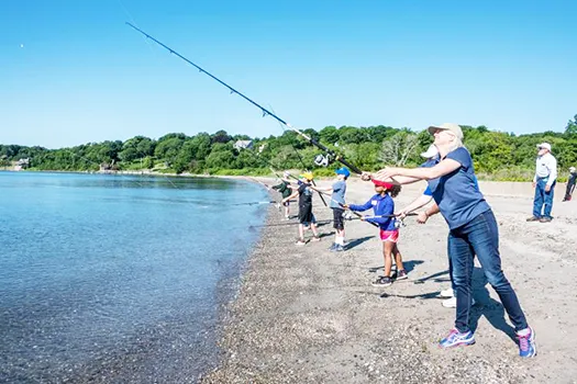 Janet Coit casts her line into the water with others in background